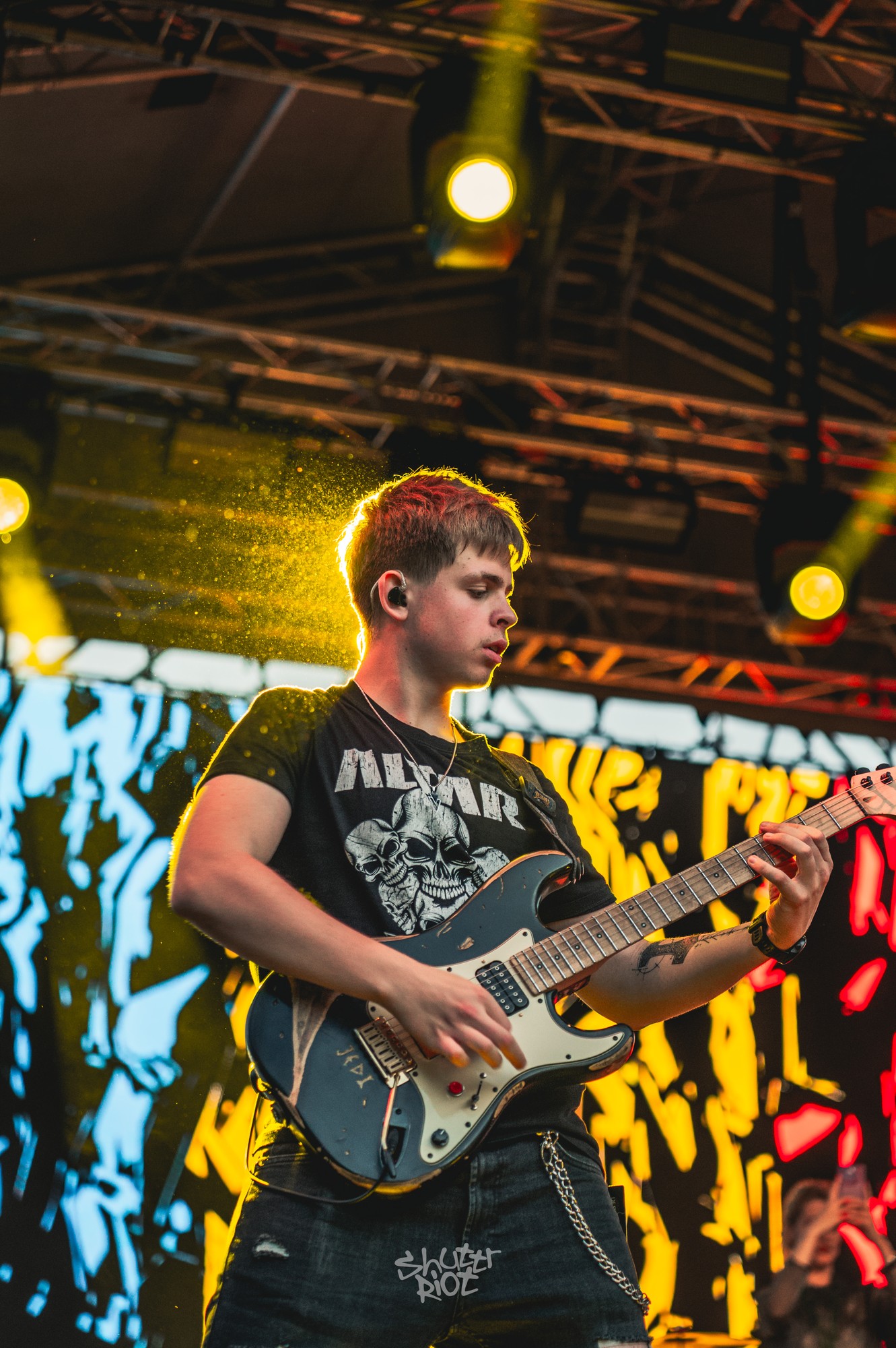 Guitarist performing beneath yellow stage lights